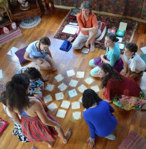 GGroup of 10-12 year old girls gathered around activity cards on the floor